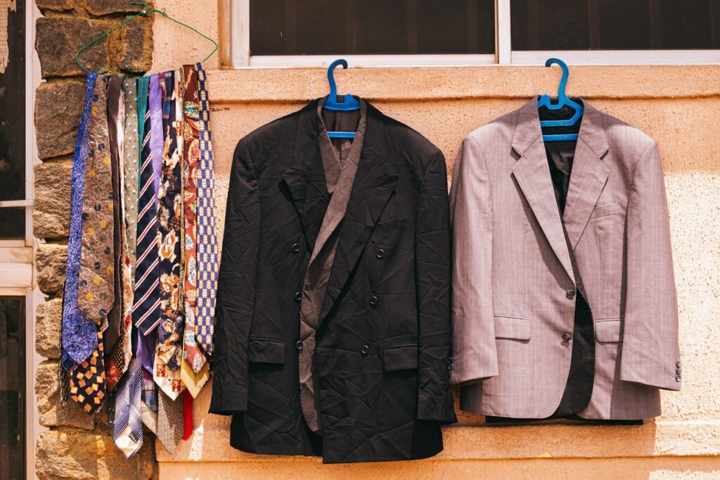A black and gray suit with colorful ties hanging outdoors on a wall in Jos, Nigeria.